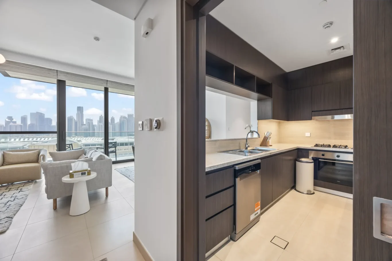 Open-plan living area with a modern dark-wood kitchen and a city skyline view through large windows.