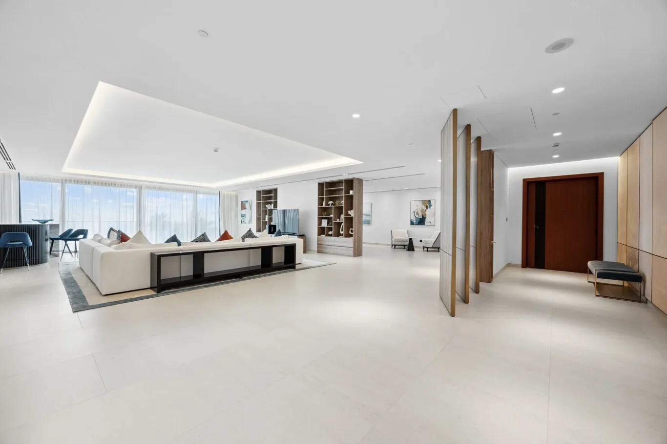 Spacious modern living room with white seating, built-in shelving, and large windows letting in natural light.