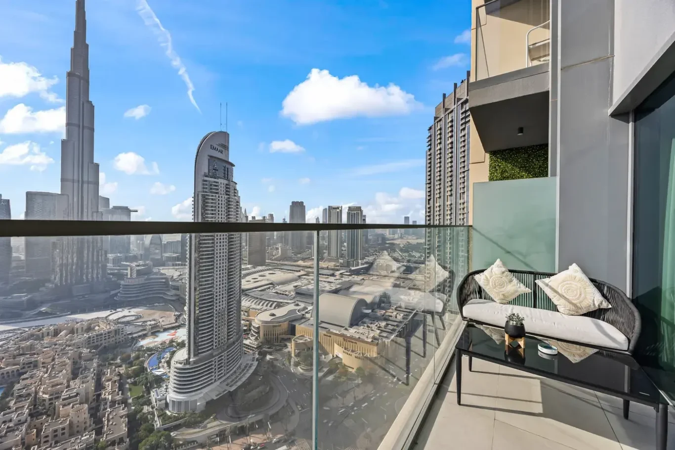 Balcony seating overlooking a Dubai cityscape with the Burj Khalifa and tall skyscrapers under a blue sky.