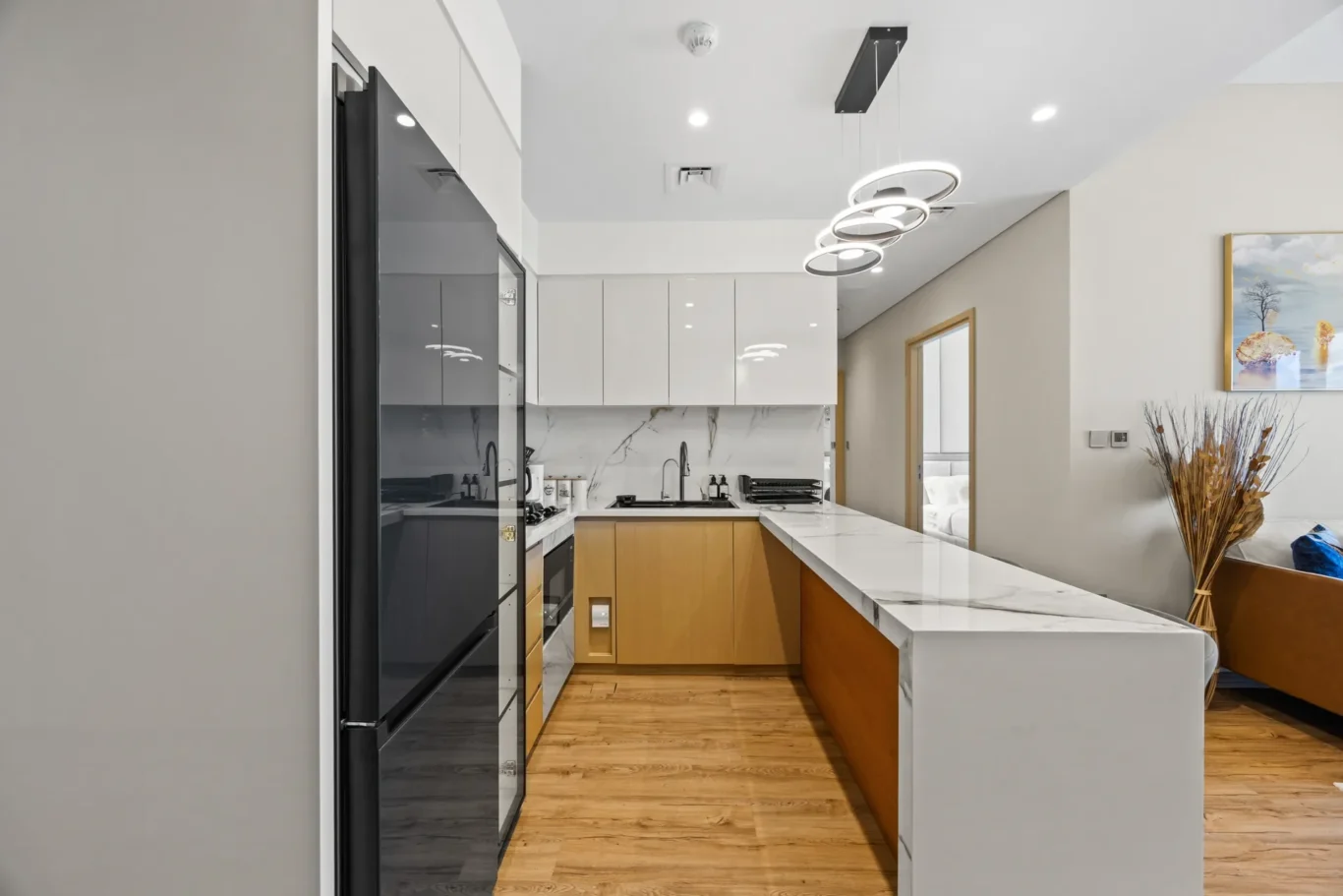 Modern kitchen with white upper cabinets, wooden lower cabinets, and a marble island countertop.