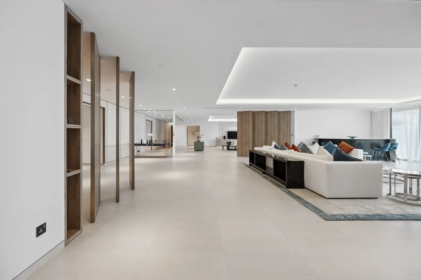Spacious modern living area with a white sectional sofa, colorful cushions, and wooden room dividers.