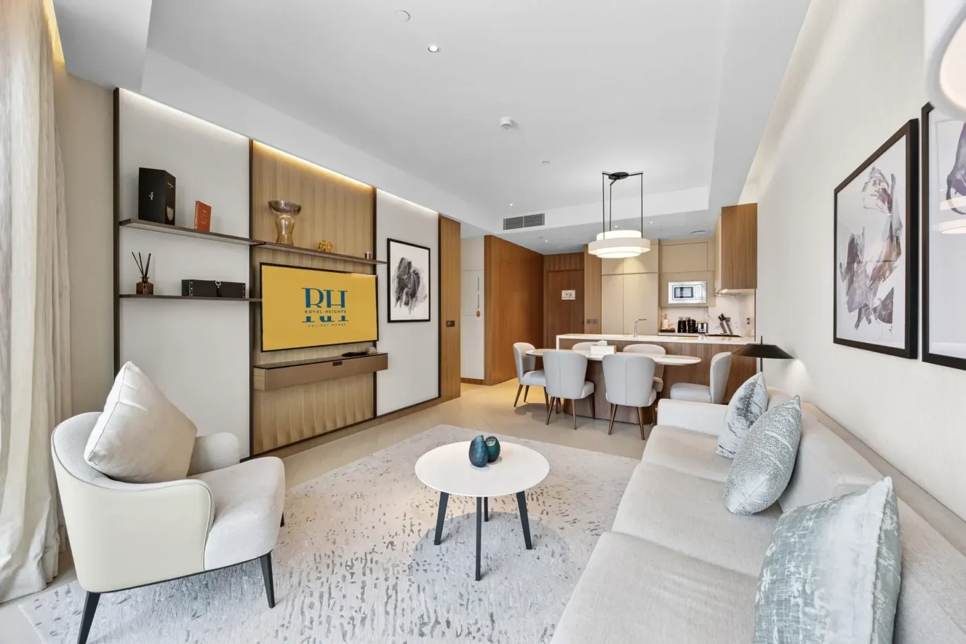 Open-concept living area with a light sofa, two armchairs, a round coffee table, and a dining nook near the kitchen.