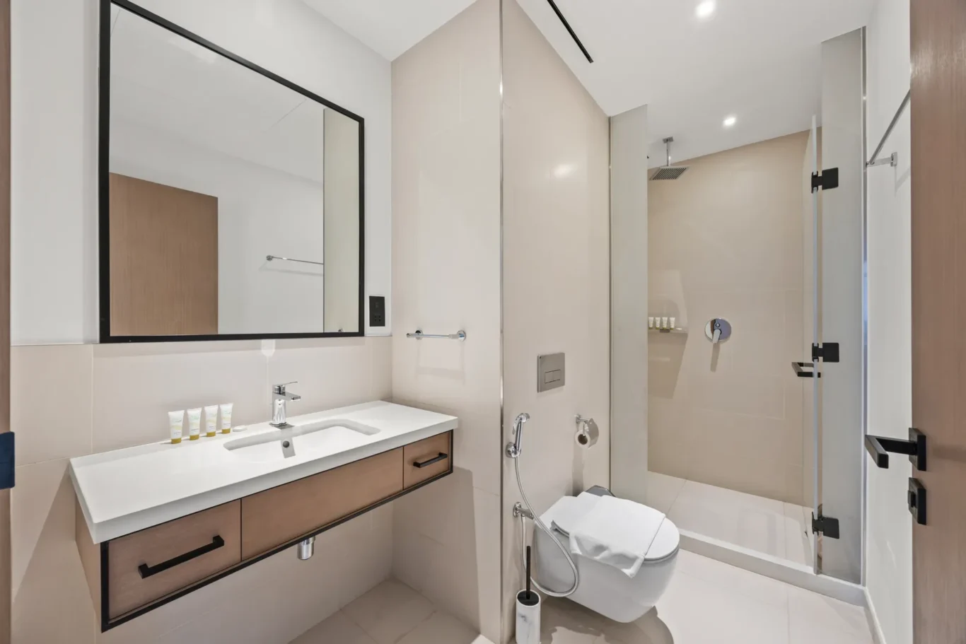 Modern bathroom with a white countertop sink, wooden vanity, and large rectangular mirror.