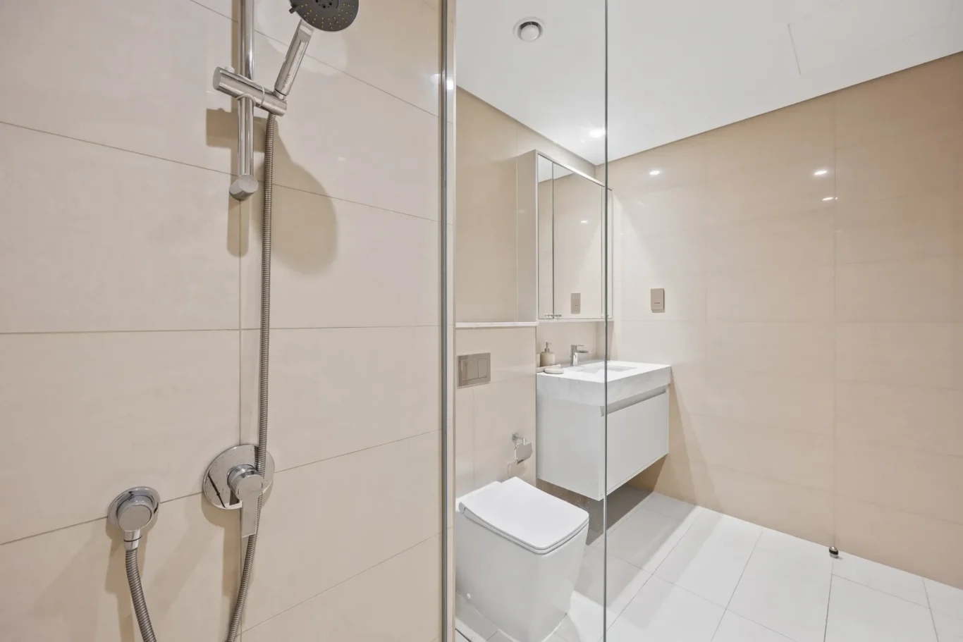 Modern bathroom with glass shower enclosure, wall-mounted shower, and white vanity.