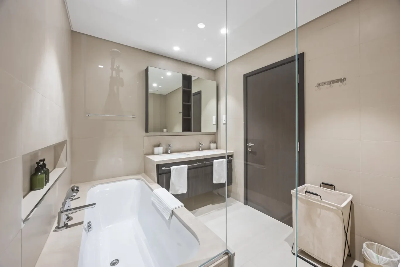 Modern bathroom with glass shower, double vanity and large mirror in neutral tones.” (informative)