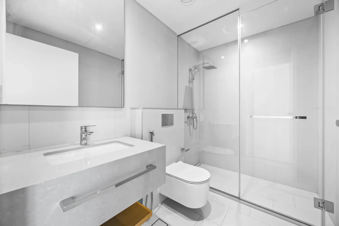 Modern bathroom with a glass shower enclosure, wall-hung toilet, and a grey marble countertop sink.