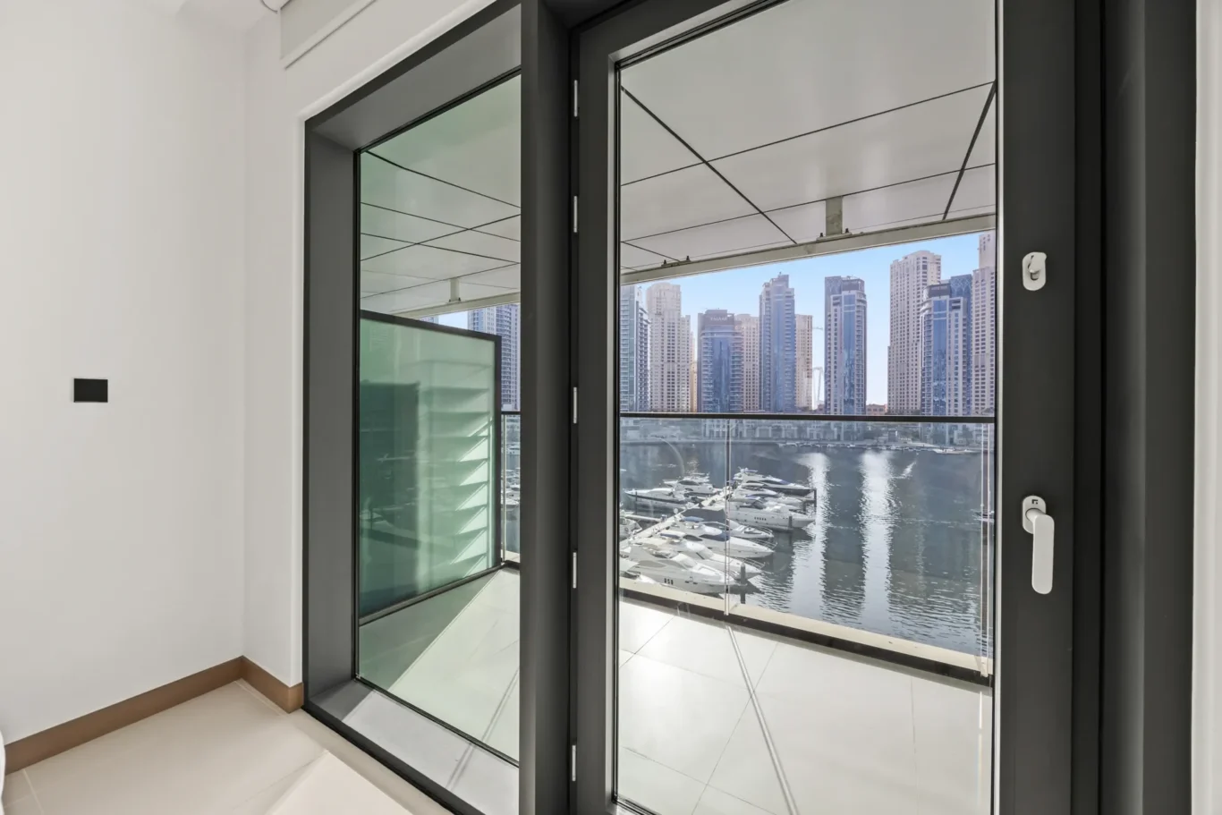 Interior space with glass balcony doors opening to a marina and high-rise cityscape outside.