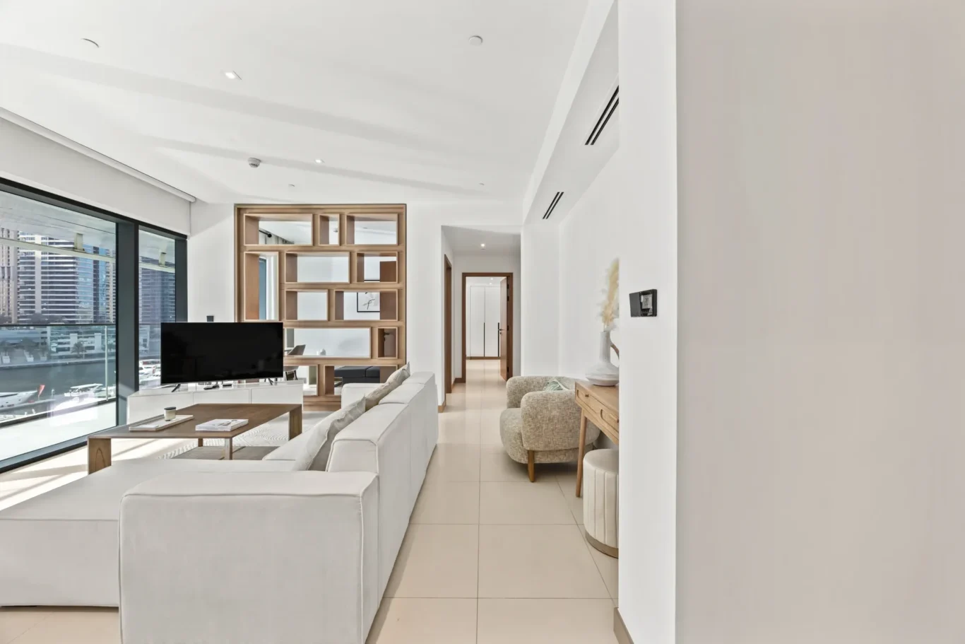 Bright modern living room with white sofas, a TV, and a large window overlooking a cityscape; wooden partition wall added for separation.