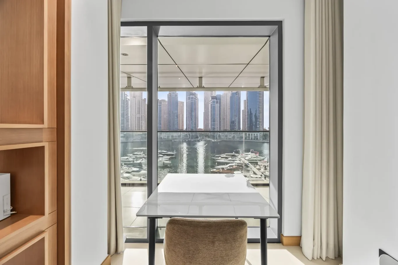 Dining nook with a glass door/window facing a marina and city skyline outside.