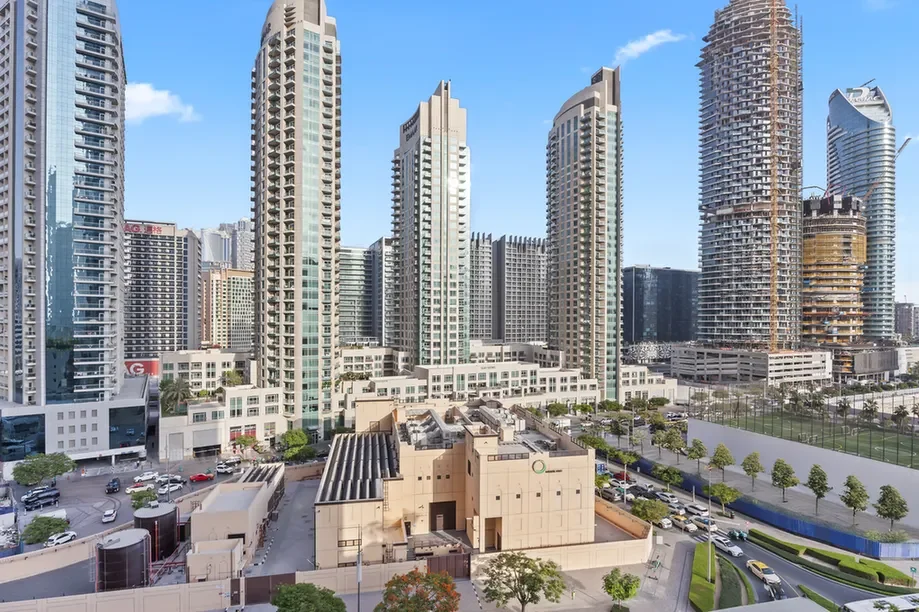 Modern city skyline with tall glass skyscrapers and a construction site against a clear blue sky
