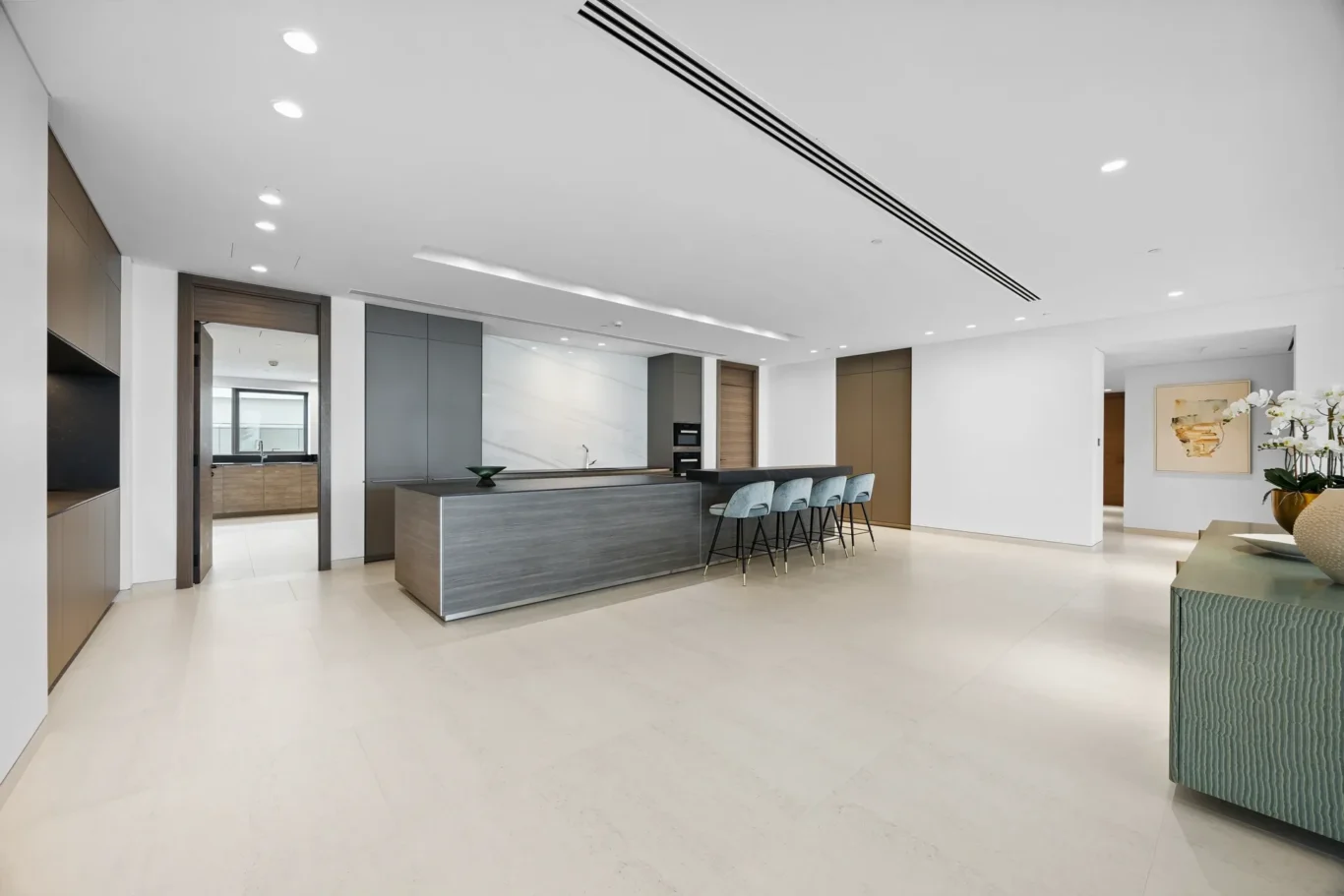 Modern open kitchen with a long gray island, gray cabinets, and a marble backsplash.