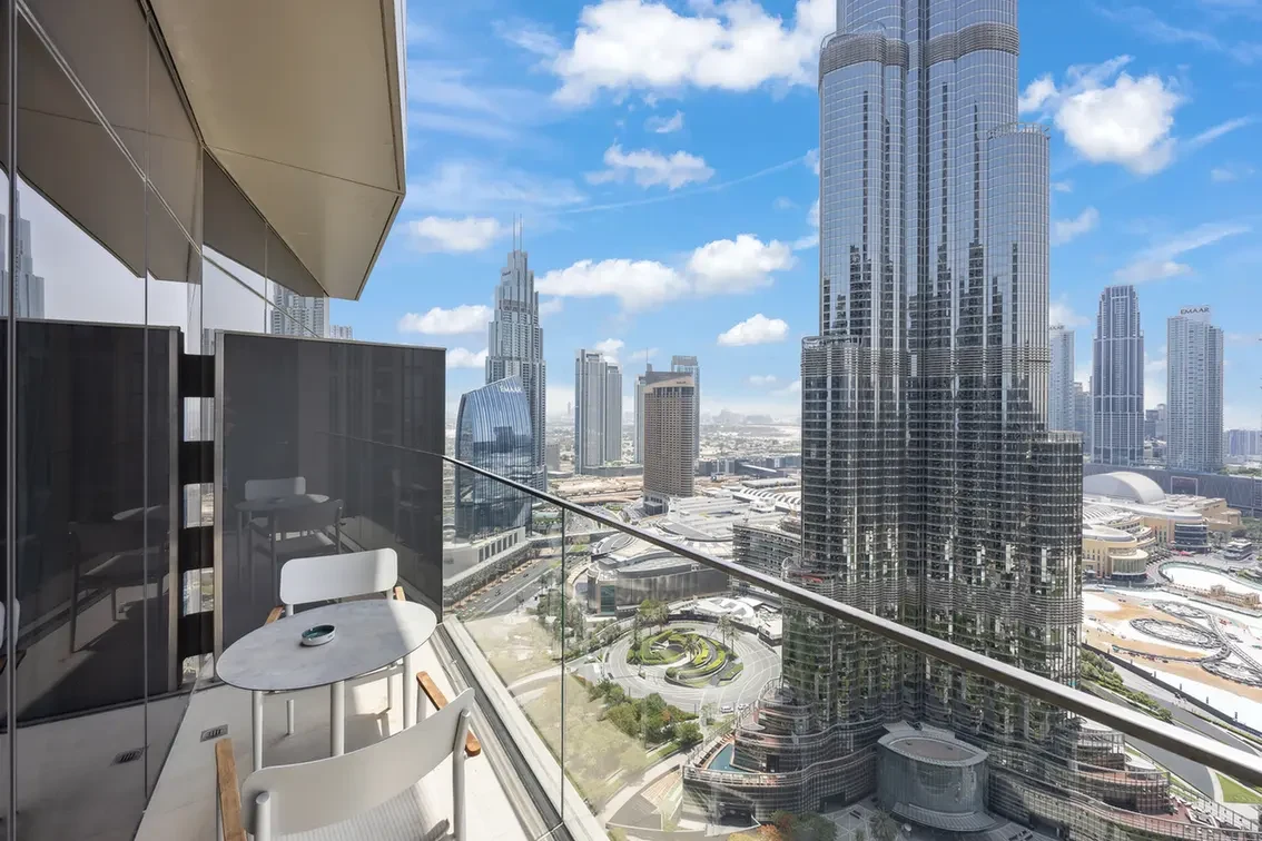 Balcony seating with a round marble table and white chairs overlooking Dubai's skyline of modern glass skyscrapers.
