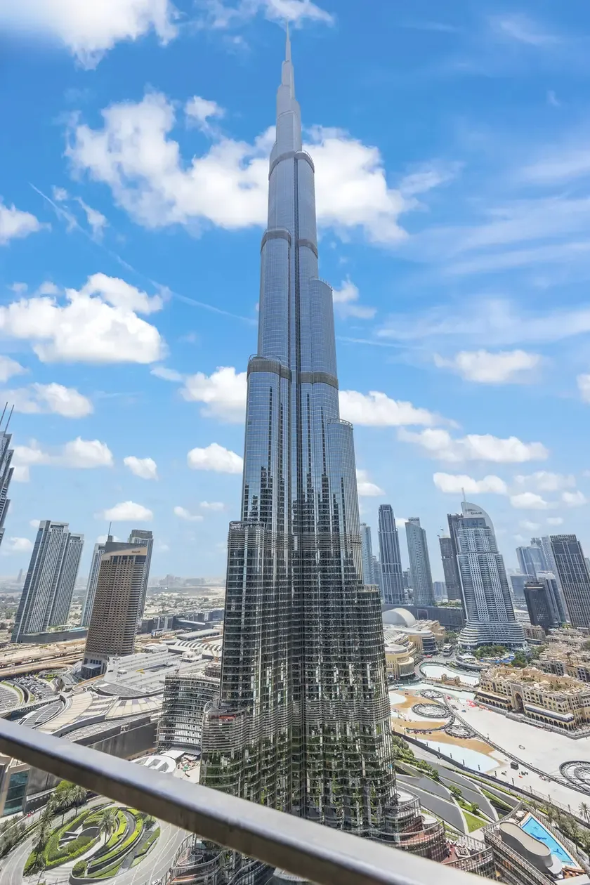 Burj Khalifa towering over Dubai with surrounding skyscrapers under a blue sky.