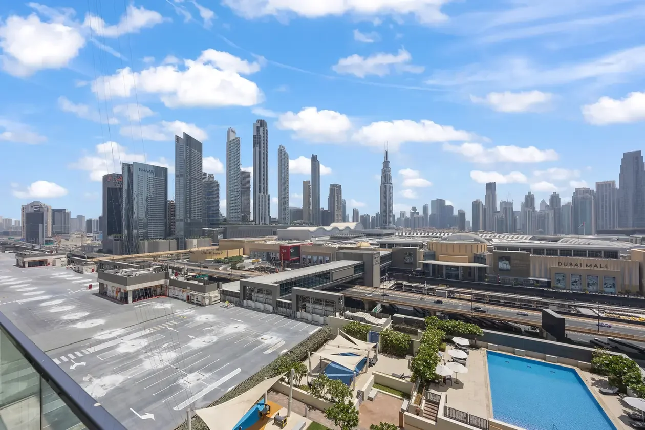 Dubai skyline with tall skyscrapers and the Dubai Mall sign, seen from a sunny rooftop pool area