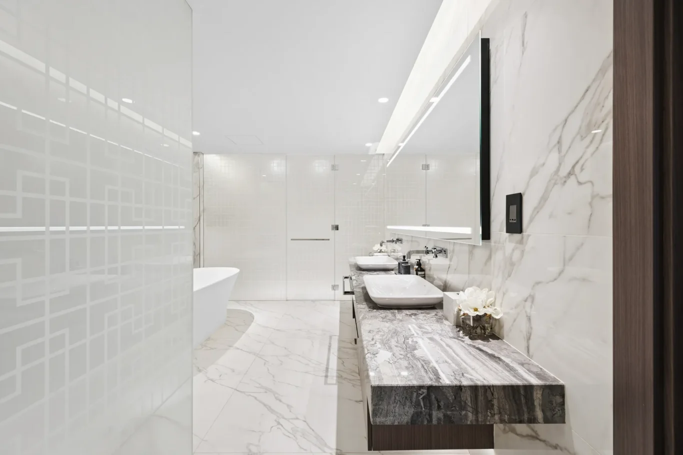 Luxurious white marble bathroom with a double vanity, large mirror, glass shower, and a freestanding tub.