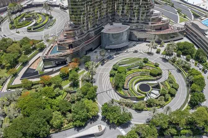 Aerial view of a modern glass office complex with circular, terraced gardens and a surrounding roundabout road.