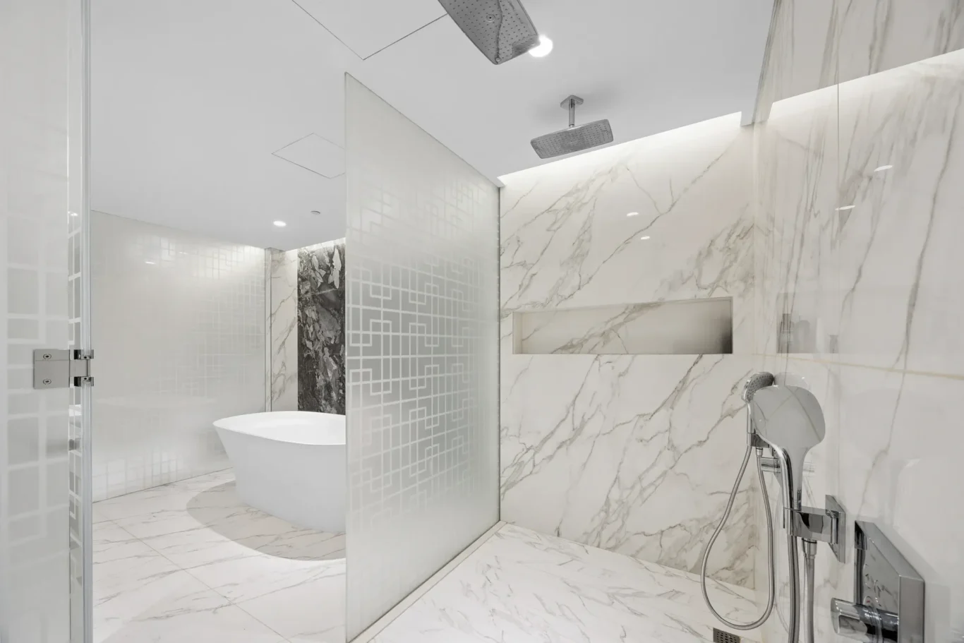 Modern marble bathroom with a glass shower partition, freestanding tub, and chrome rainfall showerhead for a spa-like look.