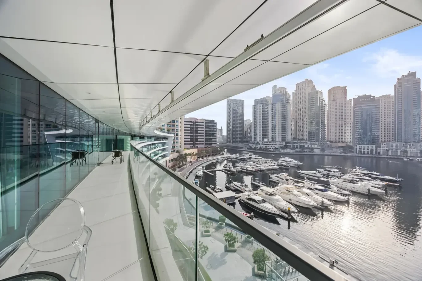 Modern waterfront balcony overlooking a marina with numerous luxury yachts and a city skyline of high-rise buildings