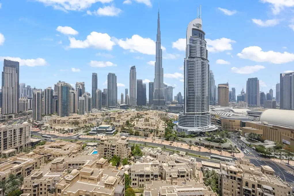 City skyline with the Burj Khalifa towering above beige residential buildings and a clear blue sky.