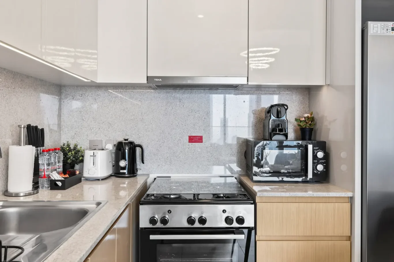 Modern kitchen countertop with white upper cabinets, stainless steel oven and stovetop, and granite backsplash.