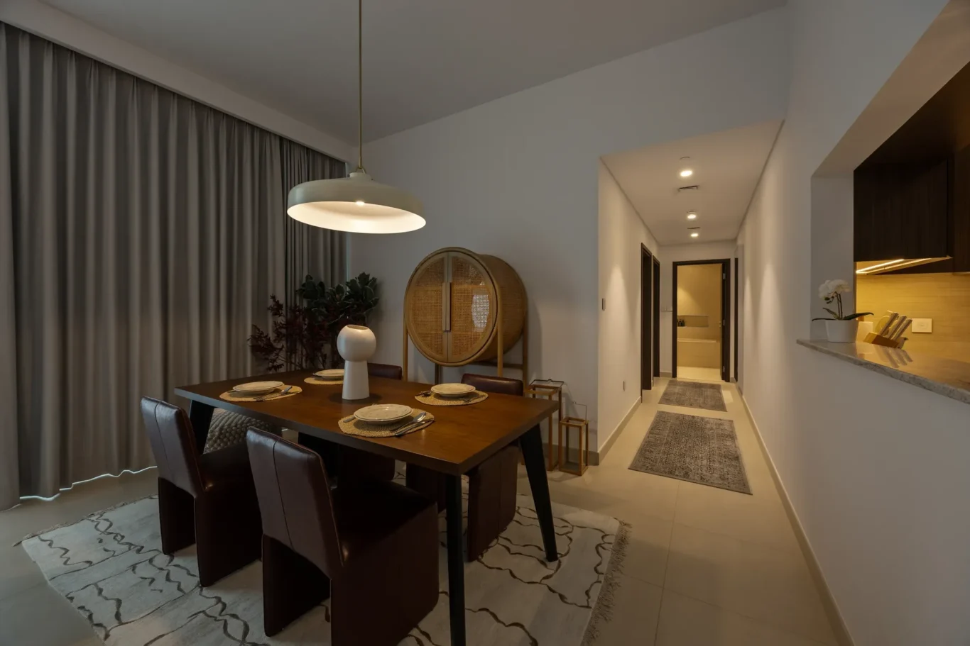 Dining room with a dark wood table set for six, large pendant light, and beige curtains along the wall.