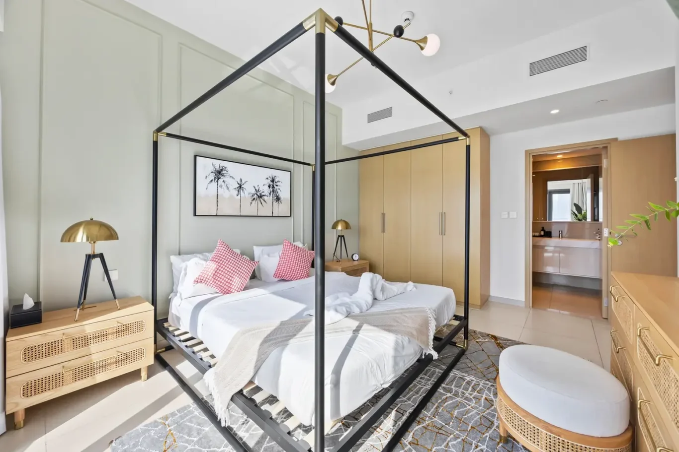 Modern bedroom with a black metal four-poster bed, white bedding, and pink accent pillows, plus wooden nightstands and wardrobe.