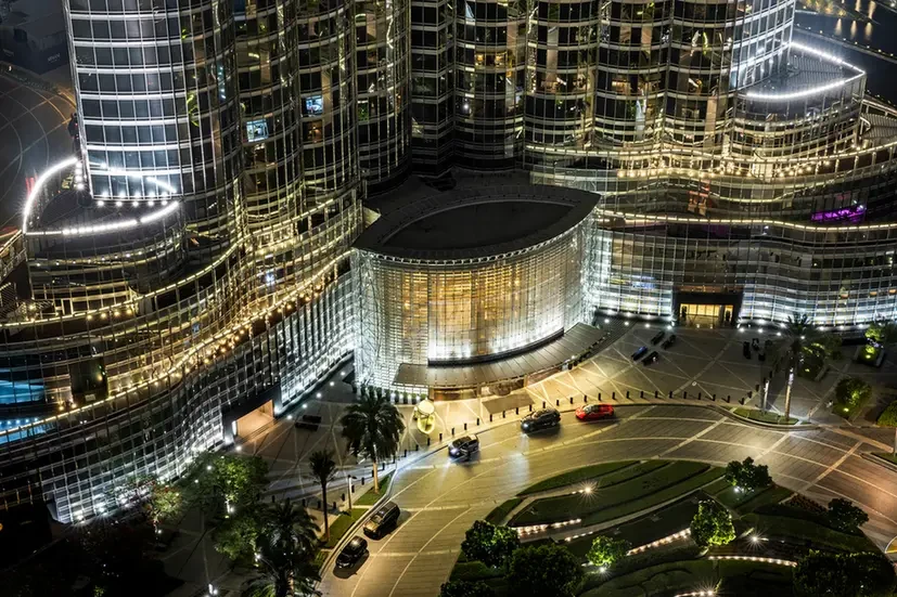 Night aerial view of a futuristic glass hotel/complex with a circular lit entrance and a curved roadway with cars at night] , but this includes extra bracket? Need valid strings. Let's craft clean.