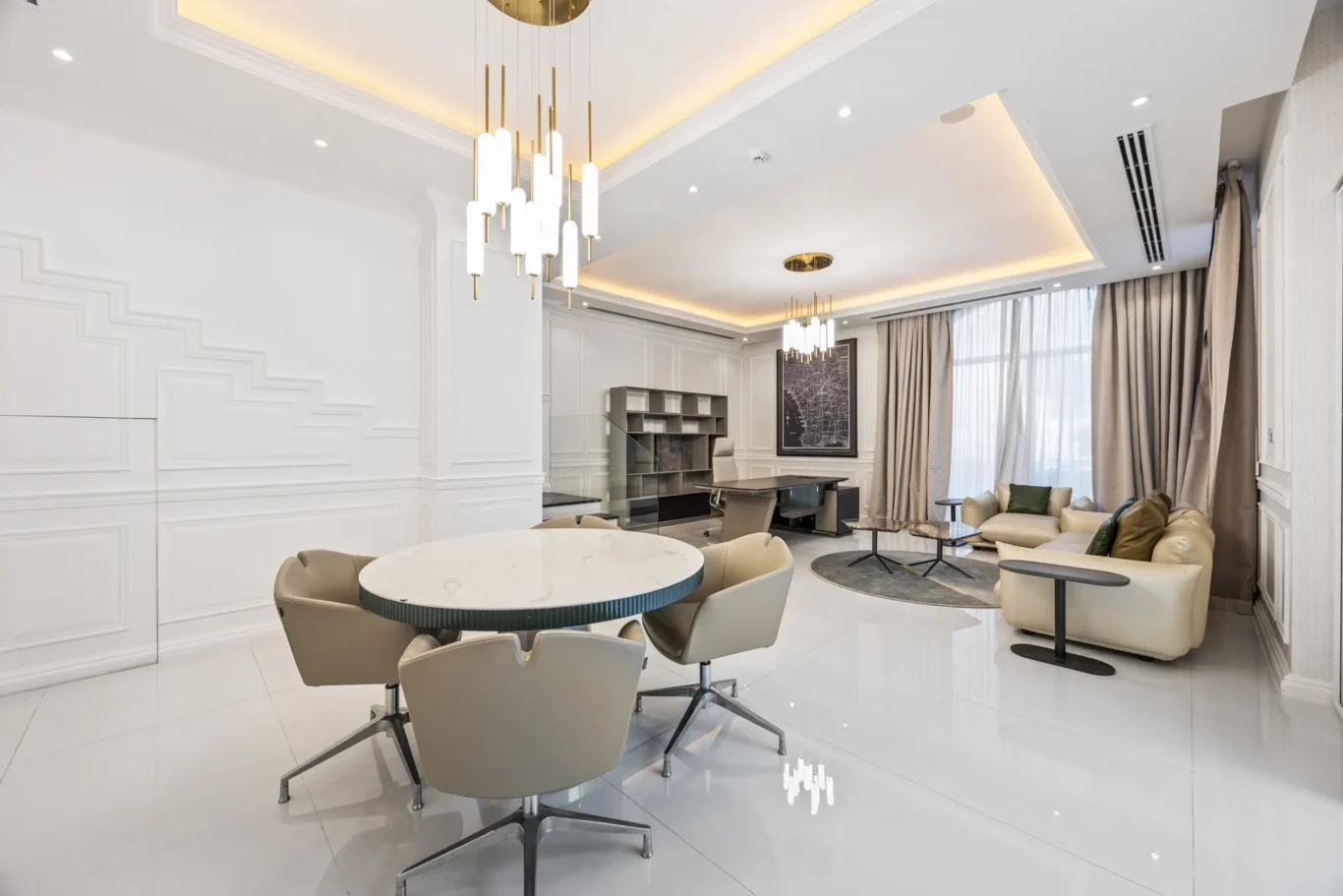 Open contemporary living room with white paneled walls, gold pendant chandelier, marble round dining table, and beige swivel chairs nearby.