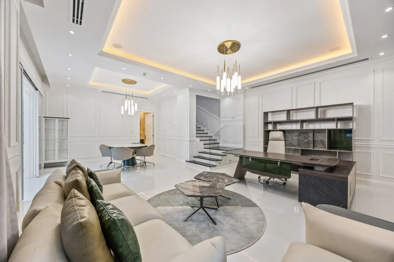 Bright white living room with a beige sectional, glass coffee tables, and a gold chandelier.