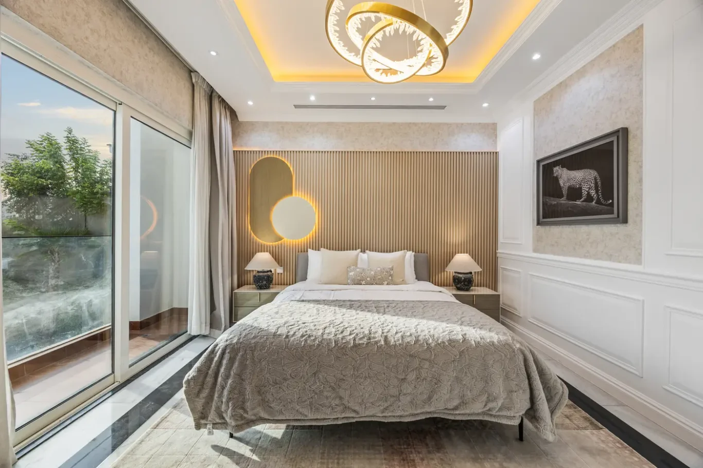 Luxurious bedroom with a beige quilt, round pendant light, and a vertical slatted headboard behind the bed.