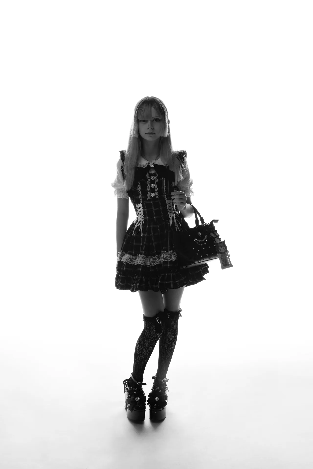 Girl in a plaid gothic Lolita dress with lace trim, thigh-high stockings and platform boots, carrying a black handbag.