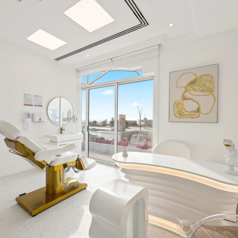 Modern dental treatment room with a white and gold reclining chair, large window, and abstract gold artwork on the wall.