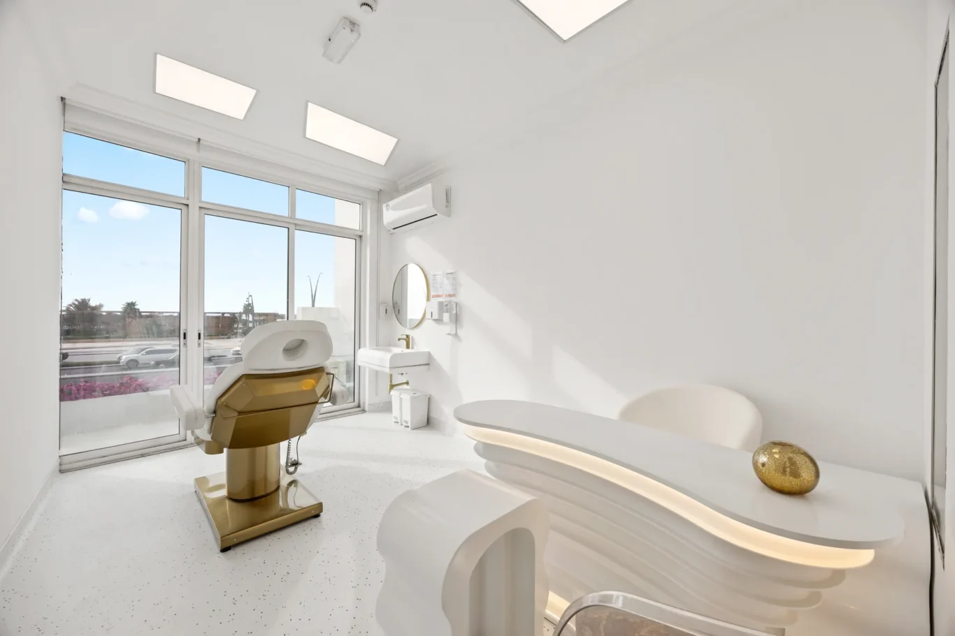 Bright dental clinic treatment room with a reclining chair, white walls, and large windows letting in natural light.