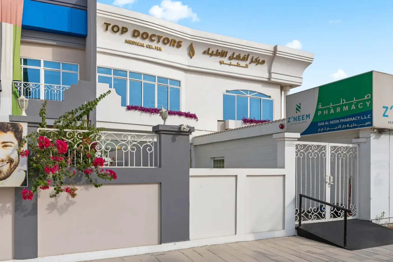 Front of a medical center with a sign reading 'Top Doctors Medical Center' and blue-tinted windows; a pharmacy sign is visible on the side.