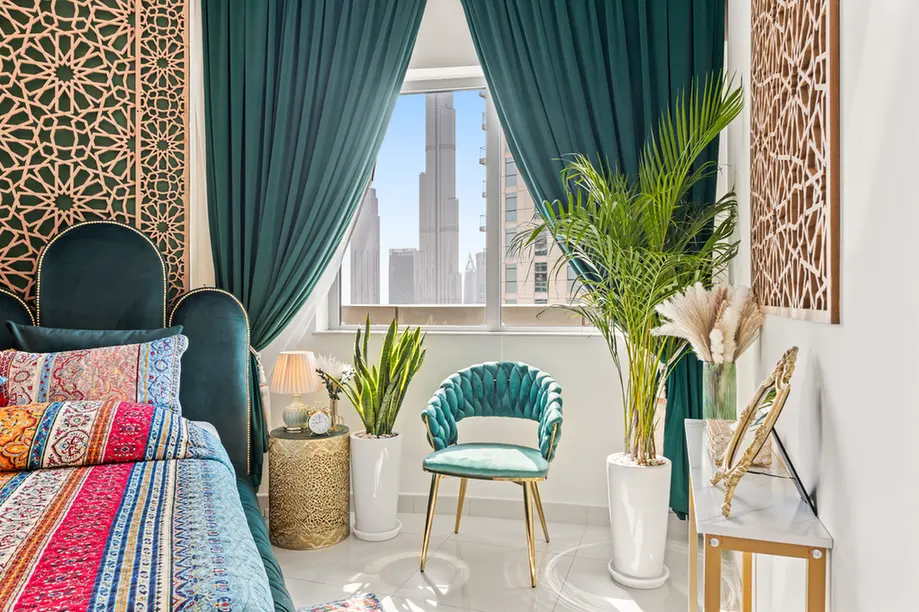 Vibrant bedroom with teal accents, decorative lattice panels, and a city skyline view through the window.