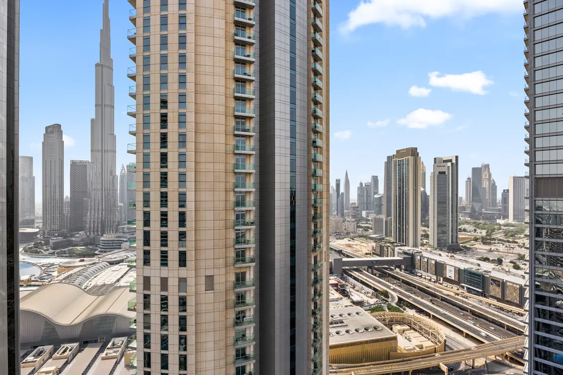 Cluster of tall high-rise buildings with a busy elevated road and rail tracks beneath on a clear day