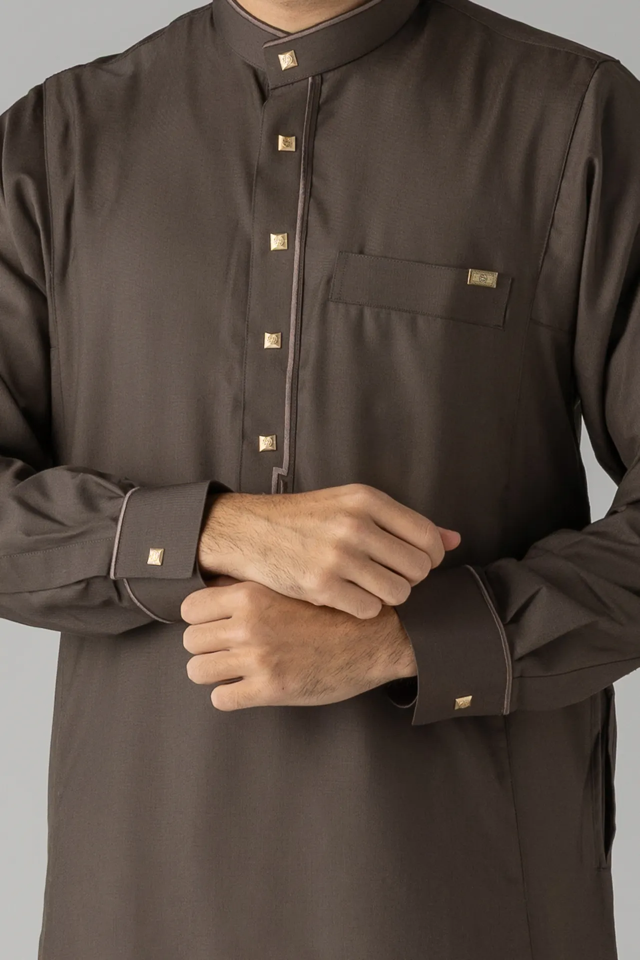 Man wearing a dark brown traditional tunic with gold square buttons and a chest pocket