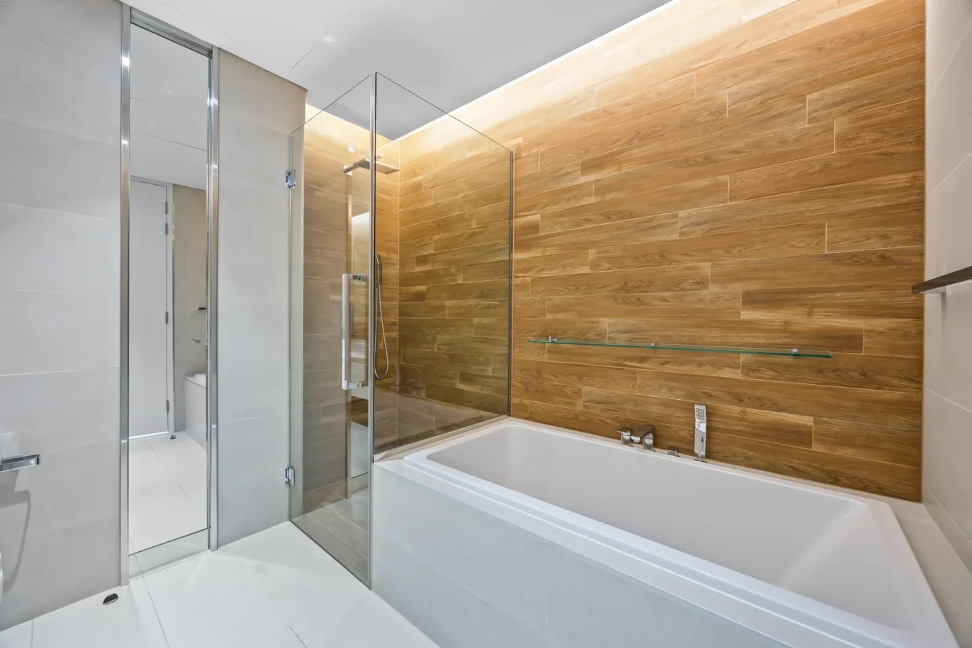 Modern bathroom with glass shower enclosure, white bathtub, and wood-look wall tiles. (informative) - concise description of the scene's key elements and style.