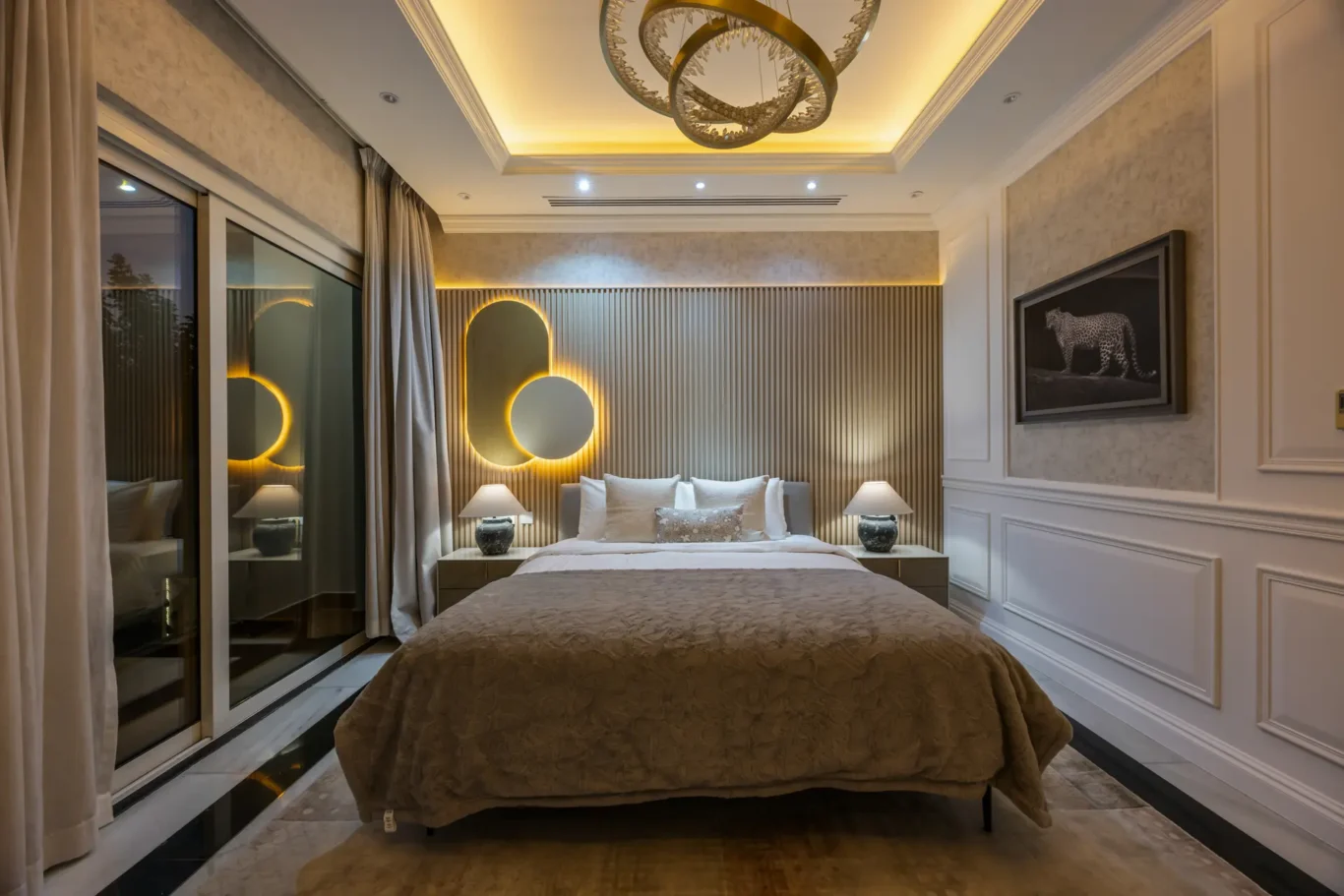 Luxurious hotel bedroom with a padded headboard, circular backlit mirrors, and warm ambient lighting across the wall.