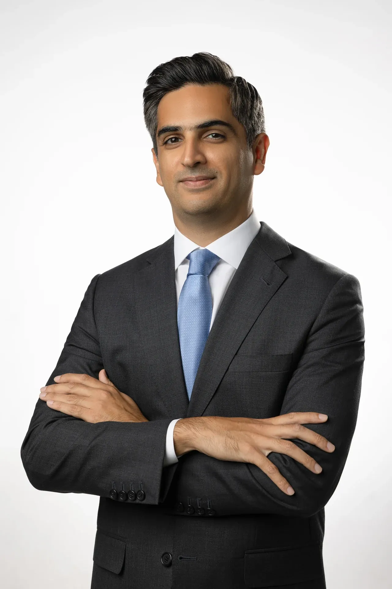 Professional man in a dark suit and blue tie, arms crossed, looking at the camera (portrait).