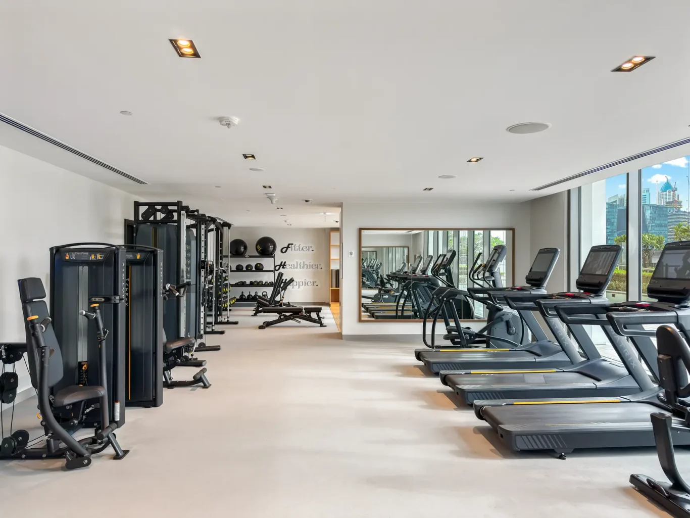 Well-lit modern gym with treadmills along a bright window wall and weight machines on the left.]**Oops**