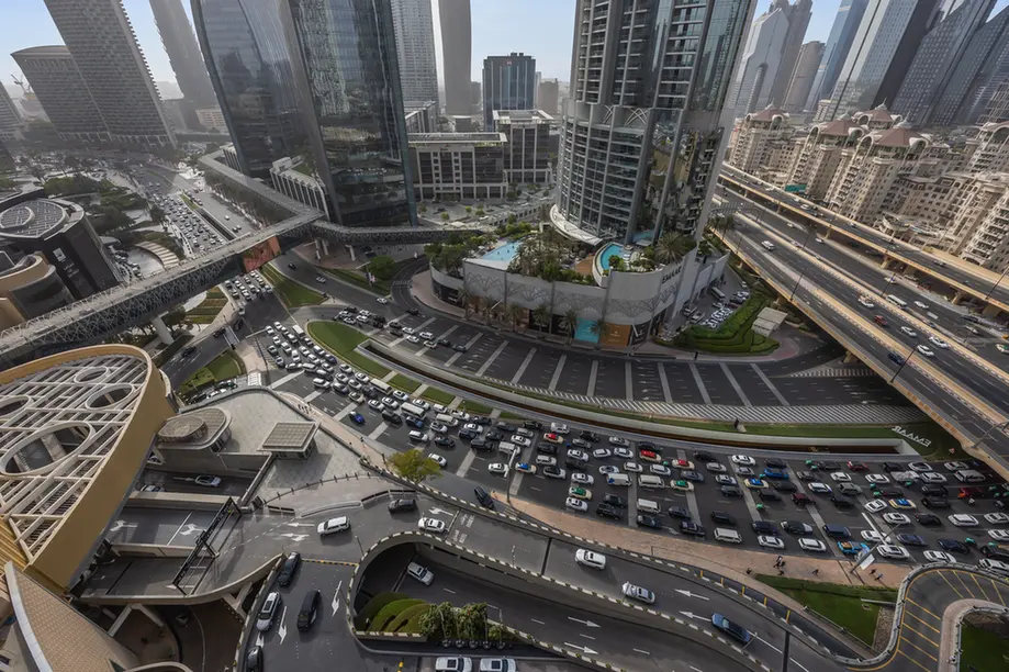 Bird's-eye view of a busy urban highway interchange surrounded by tall glass buildings and skyscrapers.