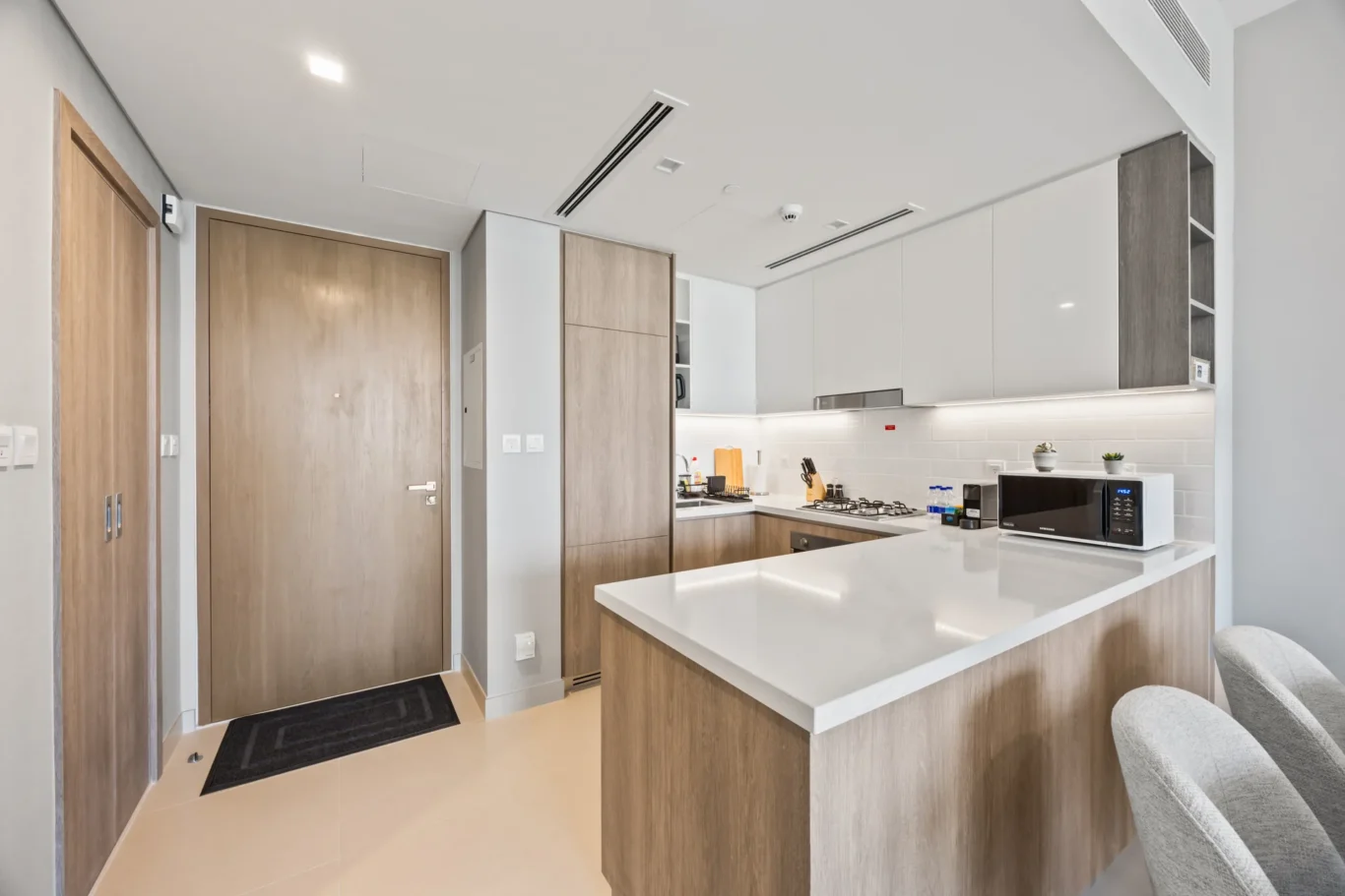 Contemporary kitchen with white upper cabinets, wood lower cabinets, and a white island with seating.