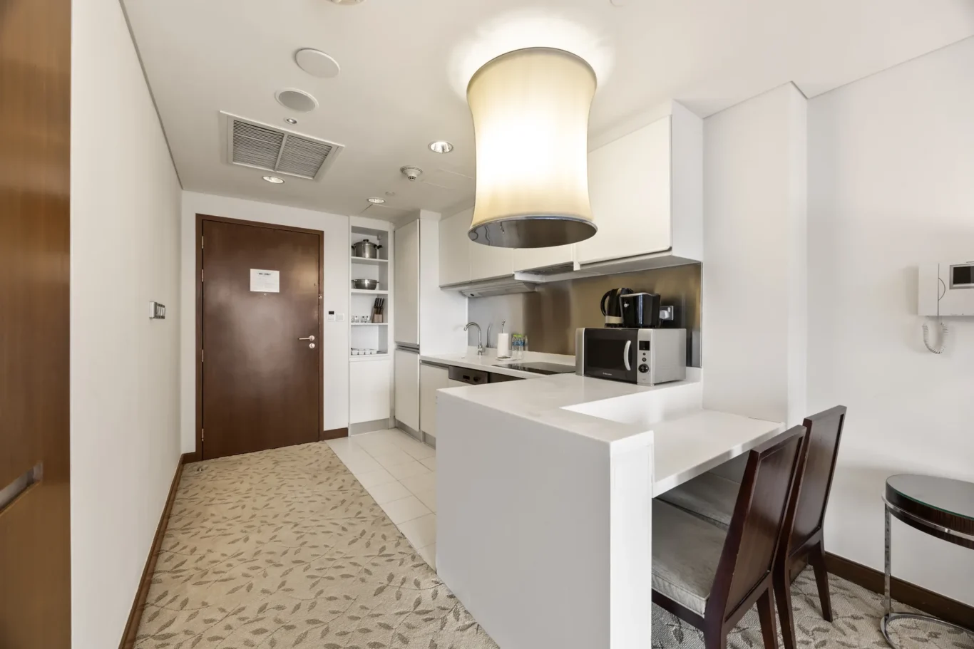 Bright modern kitchen with white cabinets, stainless appliances, and a large cylindrical pendant light over an island.