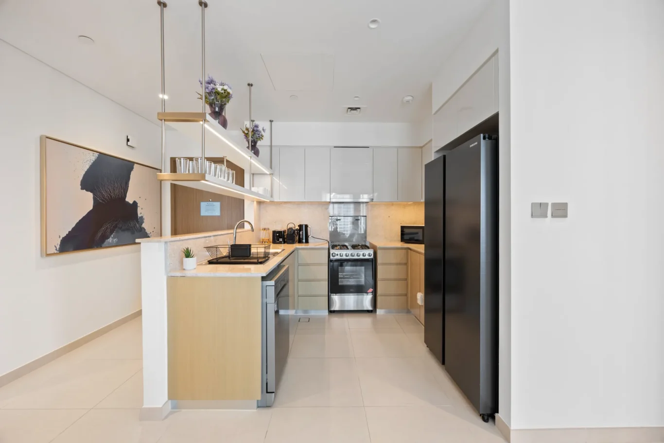 Modern kitchen with beige cabinets, island, open shelving, and stainless steel appliances on a bright, clean space.