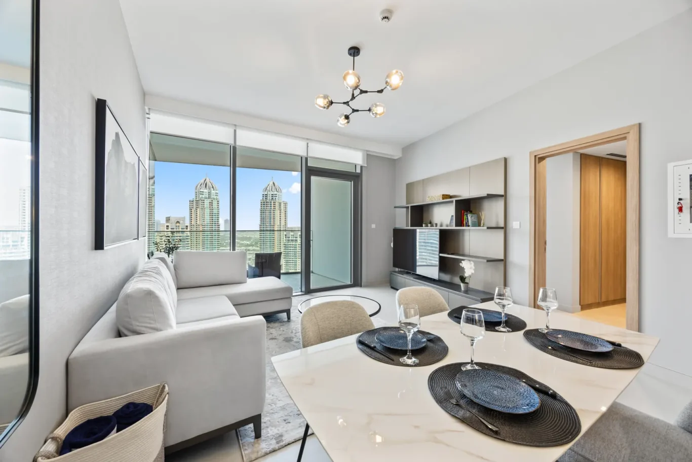 Bright open-plan living room with city skyline view through floor-to-ceiling glass doors and a white sofa.