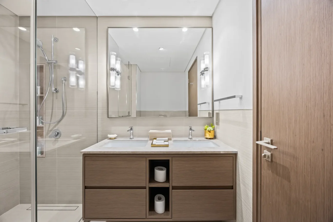 Modern bathroom with double sink vanity, large mirror, and glass-enclosed shower.