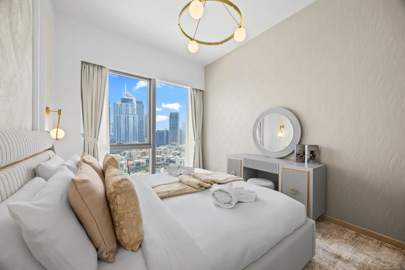 Luxurious bedroom with a large window showing a city skyline, plush bed with beige pillows, and gold-accent furniture.