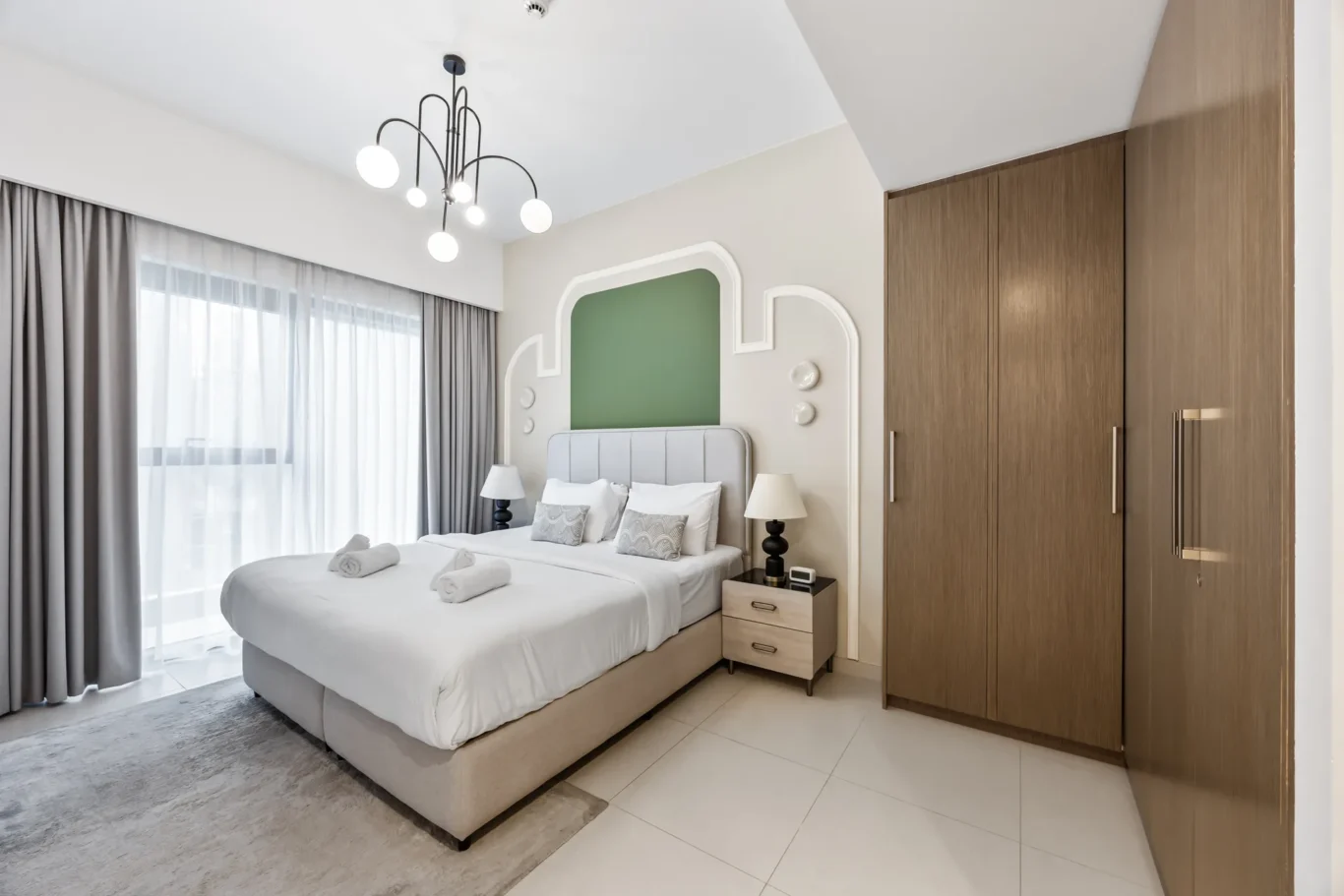 Hotel bedroom with two twin beds pushed together, white linens, and a green upholstered headboard.