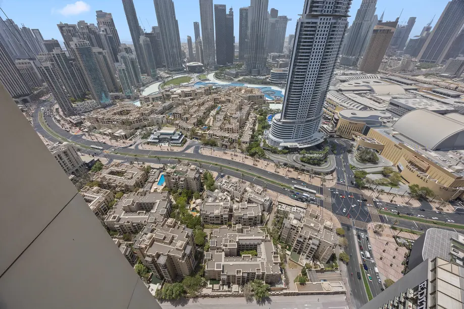 Aerial view of a dense modern city: tall skyscrapers surround a circular blue pool area and grid-like streets below.